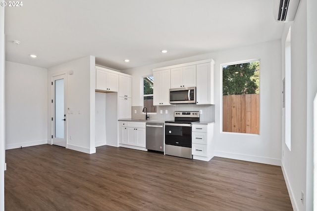 kitchen with stainless steel appliances, white cabinetry, and a wall mounted AC