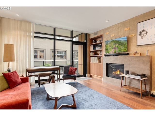 living area featuring a tiled fireplace, recessed lighting, and wood finished floors