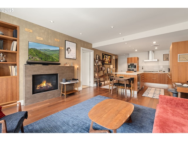 living area with a tiled fireplace, recessed lighting, and light wood-style floors