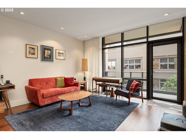 living room with baseboards, recessed lighting, wood finished floors, and a wall of windows