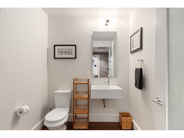 half bath featuring toilet, baseboards, and wood finished floors