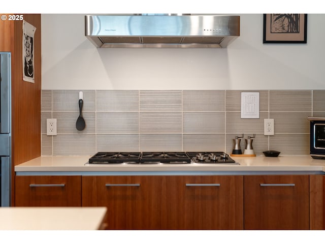 kitchen featuring decorative backsplash, modern cabinets, range hood, brown cabinets, and stainless steel gas stovetop