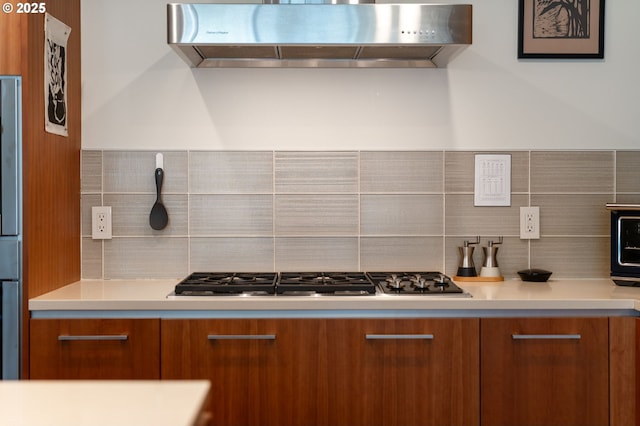 311 NW 12th Ave Unit 603, Portland, OR 97209 - kitchen featuring decorative backsplash, modern cabinets, range hood, brown cabinets, and stainless steel gas stovetop