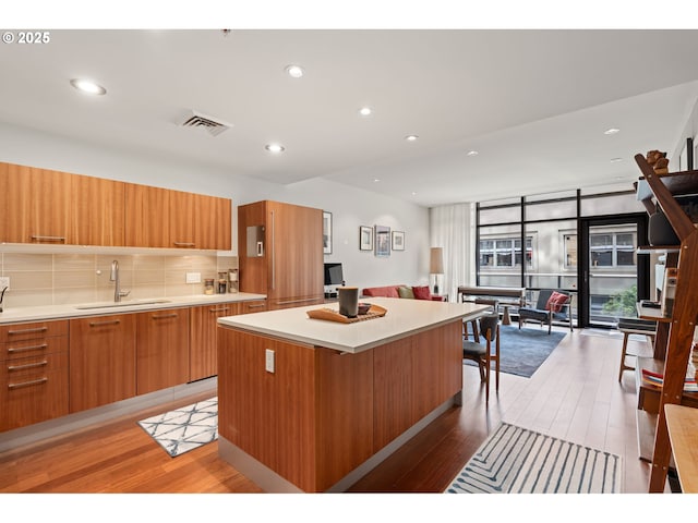 kitchen with light wood-type flooring, a sink, modern cabinets, and a center island
