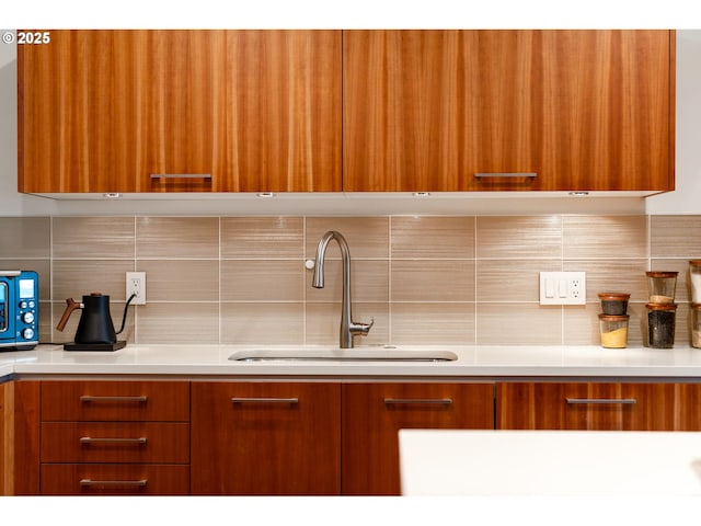 kitchen featuring brown cabinetry, decorative backsplash, a sink, and modern cabinets