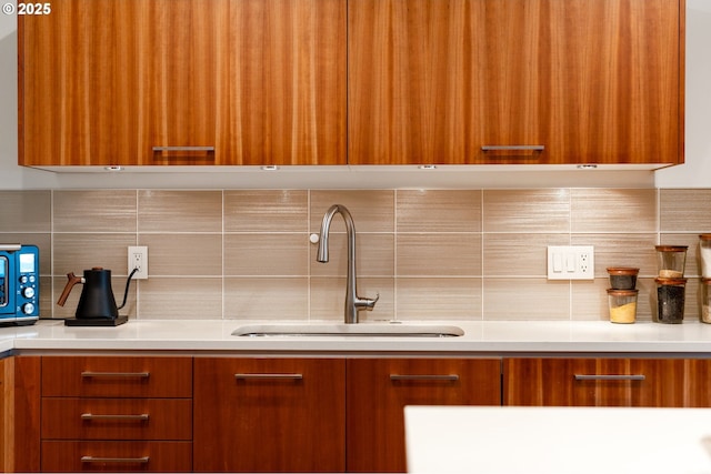 311 NW 12th Ave Unit 603, Portland, OR 97209 - kitchen featuring brown cabinetry, decorative backsplash, a sink, and modern cabinets