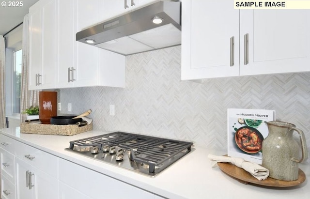 kitchen with under cabinet range hood, white cabinets, stainless steel gas cooktop, and light countertops