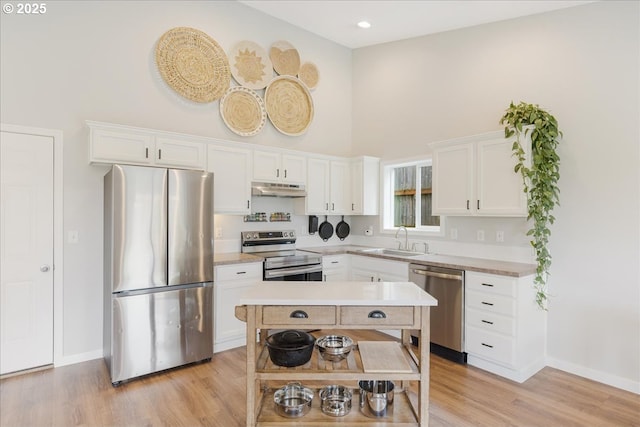 kitchen featuring a sink, a high ceiling, white cabinets, and stainless steel appliances