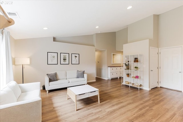 living area featuring high vaulted ceiling, baseboards, light wood finished floors, and visible vents
