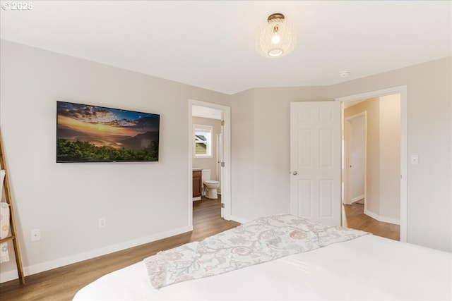 bedroom featuring baseboards, ensuite bathroom, and wood finished floors