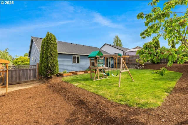 rear view of property with a yard, roof with shingles, a fenced backyard, and a playground