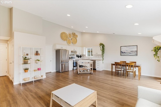 living room featuring recessed lighting, high vaulted ceiling, baseboards, and light wood finished floors