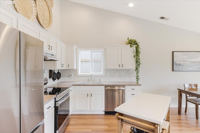 kitchen featuring white cabinets, appliances with stainless steel finishes, a sink, under cabinet range hood, and visible vents