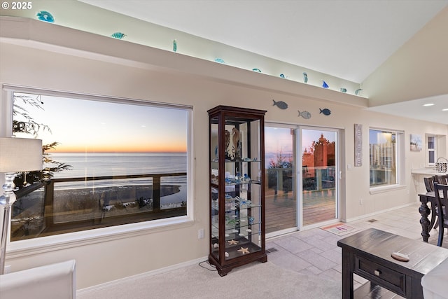 carpeted living room with lofted ceiling and a water view