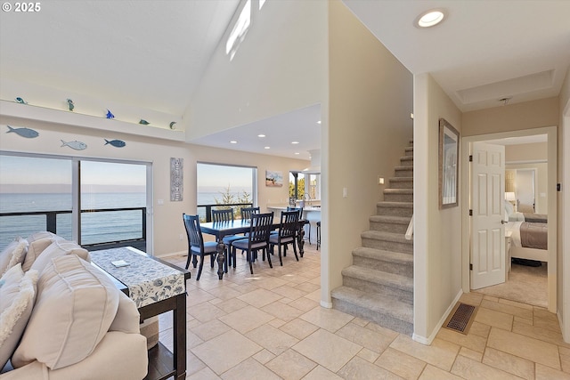 dining area with a water view and high vaulted ceiling