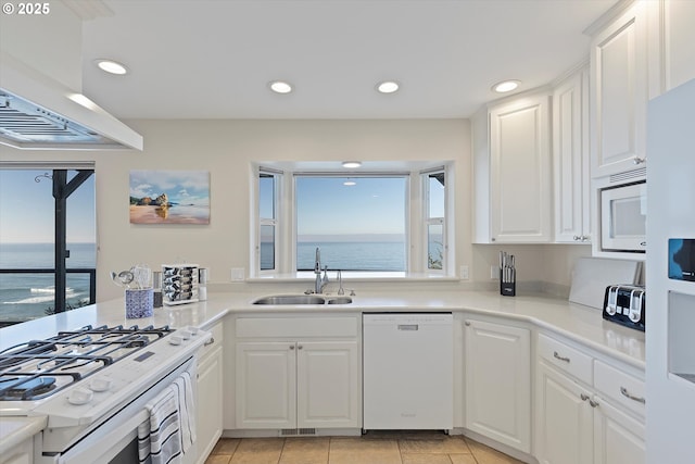 kitchen with a water view, white appliances, sink, and white cabinets