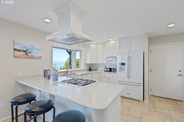 kitchen featuring island exhaust hood, high end refrigerator, white cabinets, and kitchen peninsula