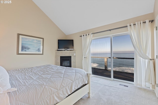 carpeted bedroom with a tile fireplace, lofted ceiling, and access to exterior