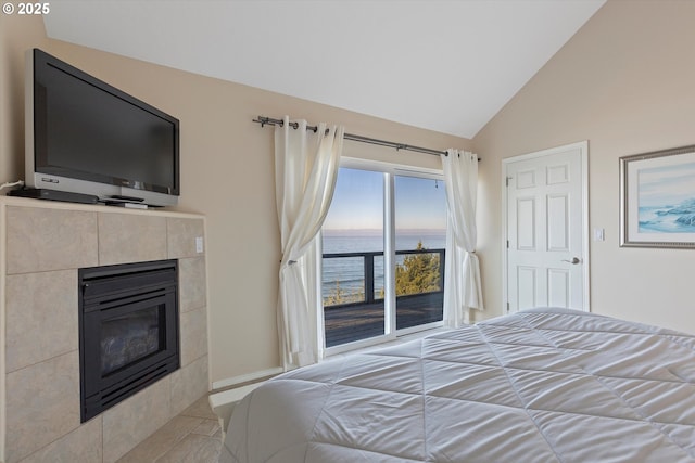 bedroom with a fireplace, access to outside, vaulted ceiling, and a water view