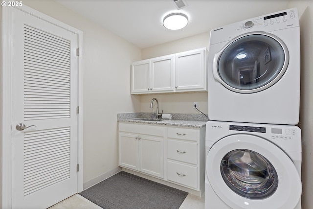 clothes washing area with stacked washer and dryer, sink, and cabinets