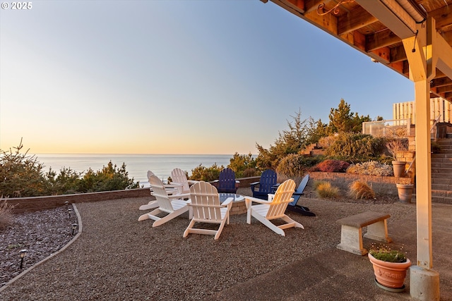 patio terrace at dusk with an outdoor fire pit and a water view