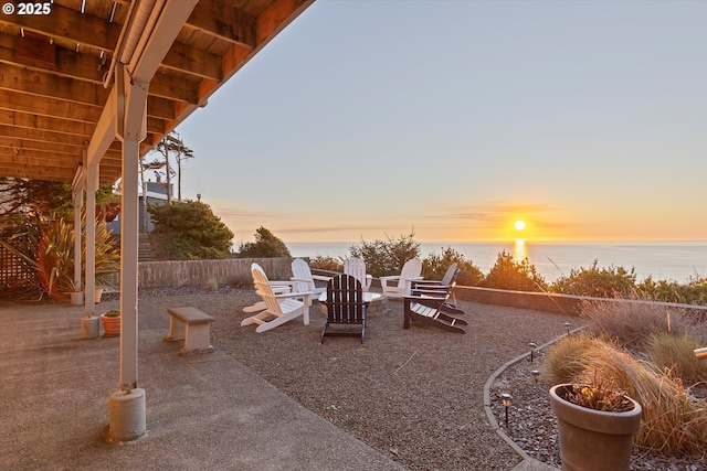 patio terrace at dusk with a water view and an outdoor fire pit