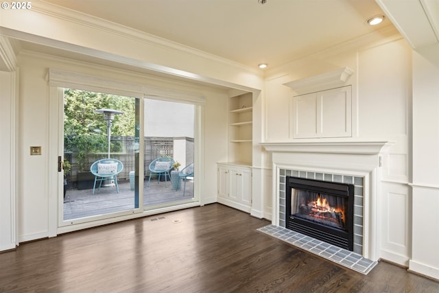 616 NW Westover Ter, Portland, OR 97210 - unfurnished living room featuring dark wood-type flooring, crown molding, a tile fireplace, built in shelves, and recessed lighting
