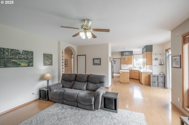 7874 Jani Ct NE, Keizer, OR 97303 - living area with arched walkways, light wood-style floors, ceiling fan, and baseboards