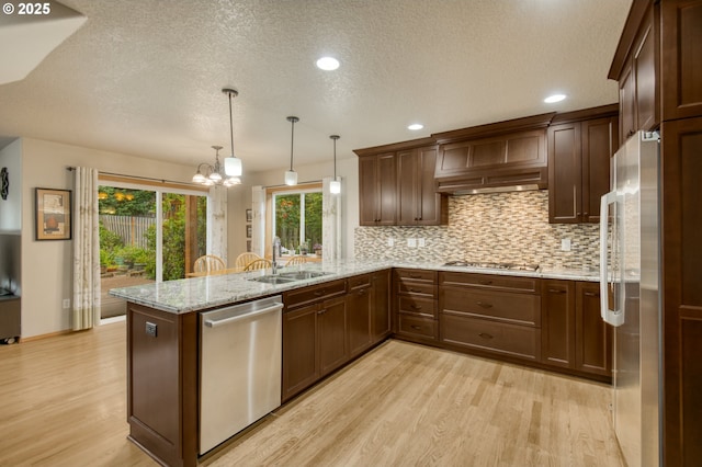 5200 NW 168th Pl, Portland, OR 97229 - kitchen with appliances with stainless steel finishes, a sink, light wood-style floors, a peninsula, and backsplash