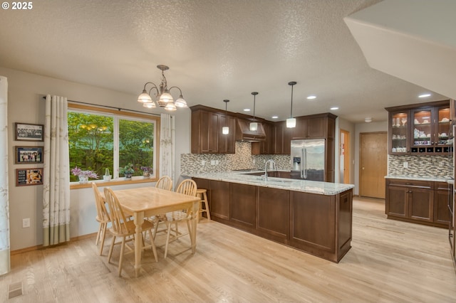5200 NW 168th Pl, Portland, OR 97229 - kitchen featuring stainless steel refrigerator with ice dispenser, tasteful backsplash, wall chimney exhaust hood, a peninsula, and light wood finished floors