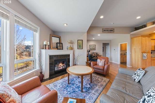 living room with a healthy amount of sunlight, a fireplace, and light hardwood / wood-style flooring