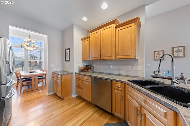 kitchen with sink, backsplash, a chandelier, stainless steel appliances, and light hardwood / wood-style flooring