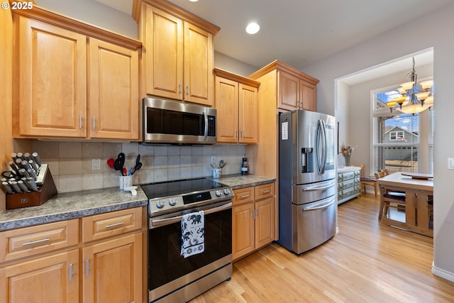 kitchen featuring tasteful backsplash, light hardwood / wood-style flooring, a chandelier, and appliances with stainless steel finishes