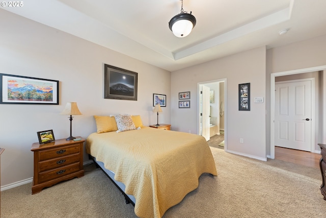 bedroom featuring connected bathroom, a raised ceiling, and carpet