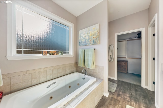 bathroom with a relaxing tiled tub and wood-type flooring