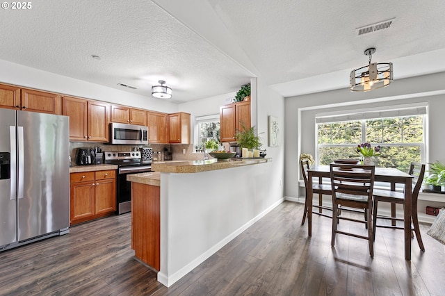 30366 SW Ruth St Unit 70, Wilsonville, OR 97070 - kitchen with brown cabinets, stainless steel appliances, visible vents, and dark wood-style flooring
