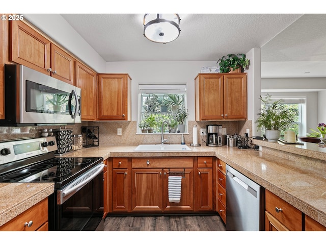 kitchen with plenty of natural light, tile countertops, a sink, dark wood finished floors, and stainless steel appliances