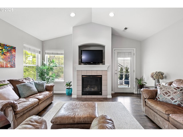 living room with plenty of natural light, lofted ceiling, and a tiled fireplace