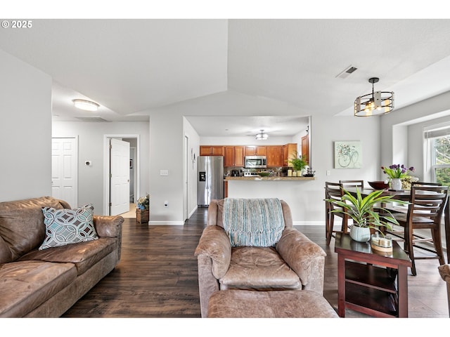 living area with dark wood-style flooring, a chandelier, baseboards, lofted ceiling, and visible vents