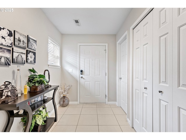 doorway to outside with baseboards, visible vents, and light tile patterned floors
