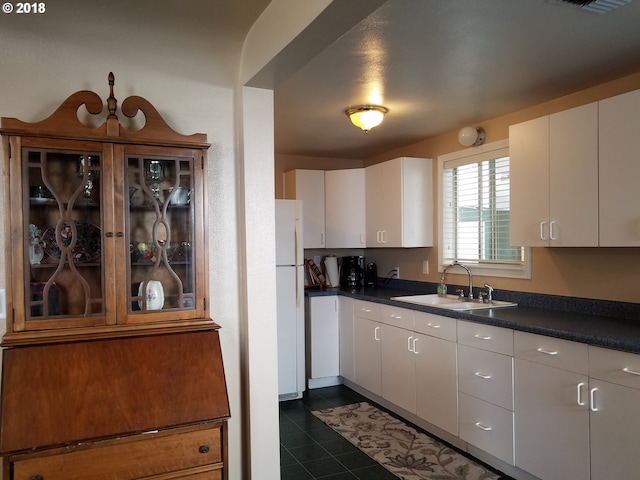 335 Kourt Dr, Eugene, OR 97404 - kitchen with freestanding refrigerator, dark countertops, dark tile patterned flooring, and white cabinetry
