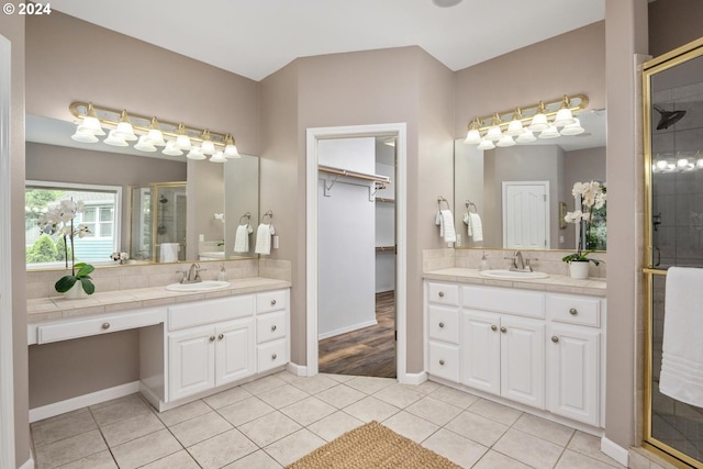 bathroom featuring vanity, a shower with shower door, tile patterned floors, and tasteful backsplash