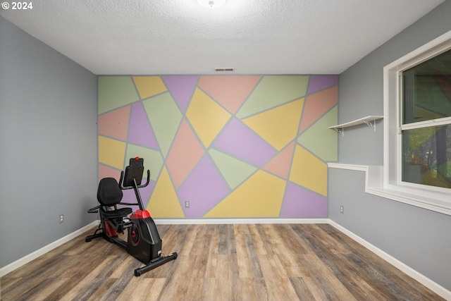 exercise room with wood-type flooring and a textured ceiling