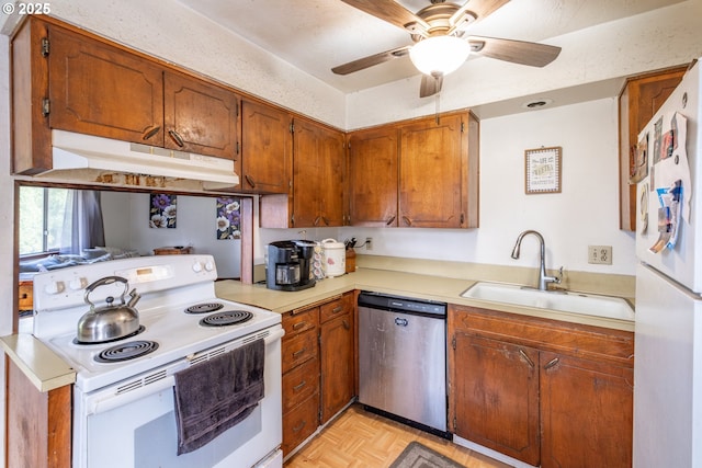 kitchen with brown cabinets, under cabinet range hood, a sink, white appliances, and light countertops