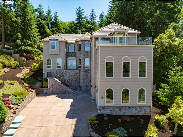 3169 Tanner Park Dr, Eugene, OR 97405 - view of front facade featuring a balcony, a patio, stairs, and stone siding