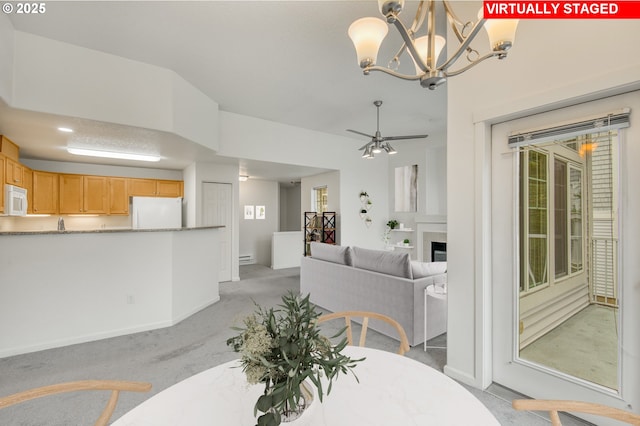 dining space featuring light colored carpet, a wealth of natural light, and ceiling fan with notable chandelier