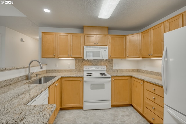 kitchen featuring light brown cabinetry, sink, white appliances, and light stone countertops