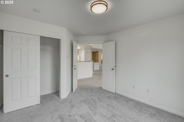 unfurnished bedroom with light carpet, a closet, and a textured ceiling