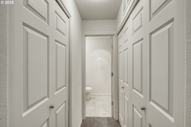 corridor with a textured ceiling and carpet floors