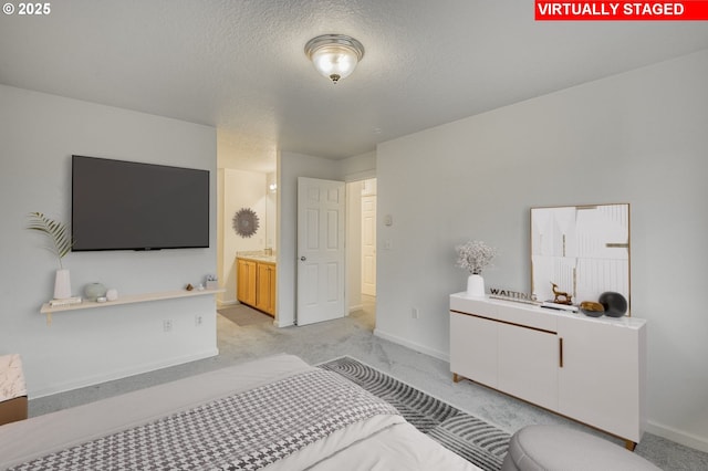 carpeted bedroom featuring a textured ceiling and ensuite bathroom